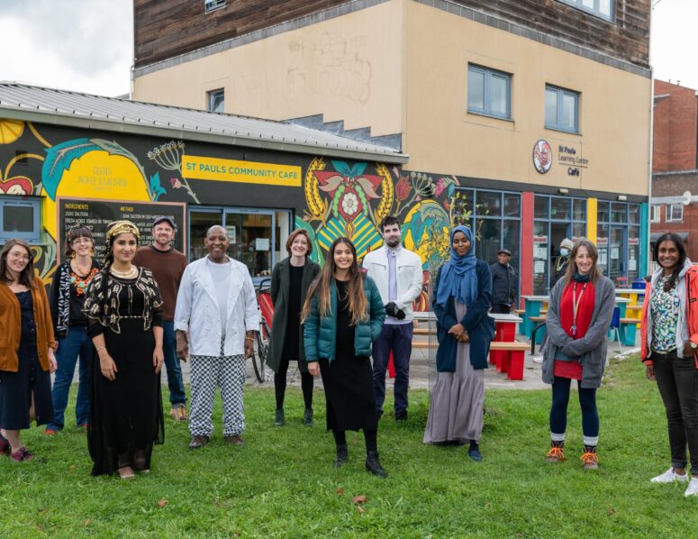 Community and project contributors standing in front of the St Pauls Community Cafe , new outdoor street furniture and colourful murals